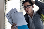 Man looking at stack of bills with stressed look