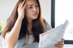 Women with concerned look on her face holding bills